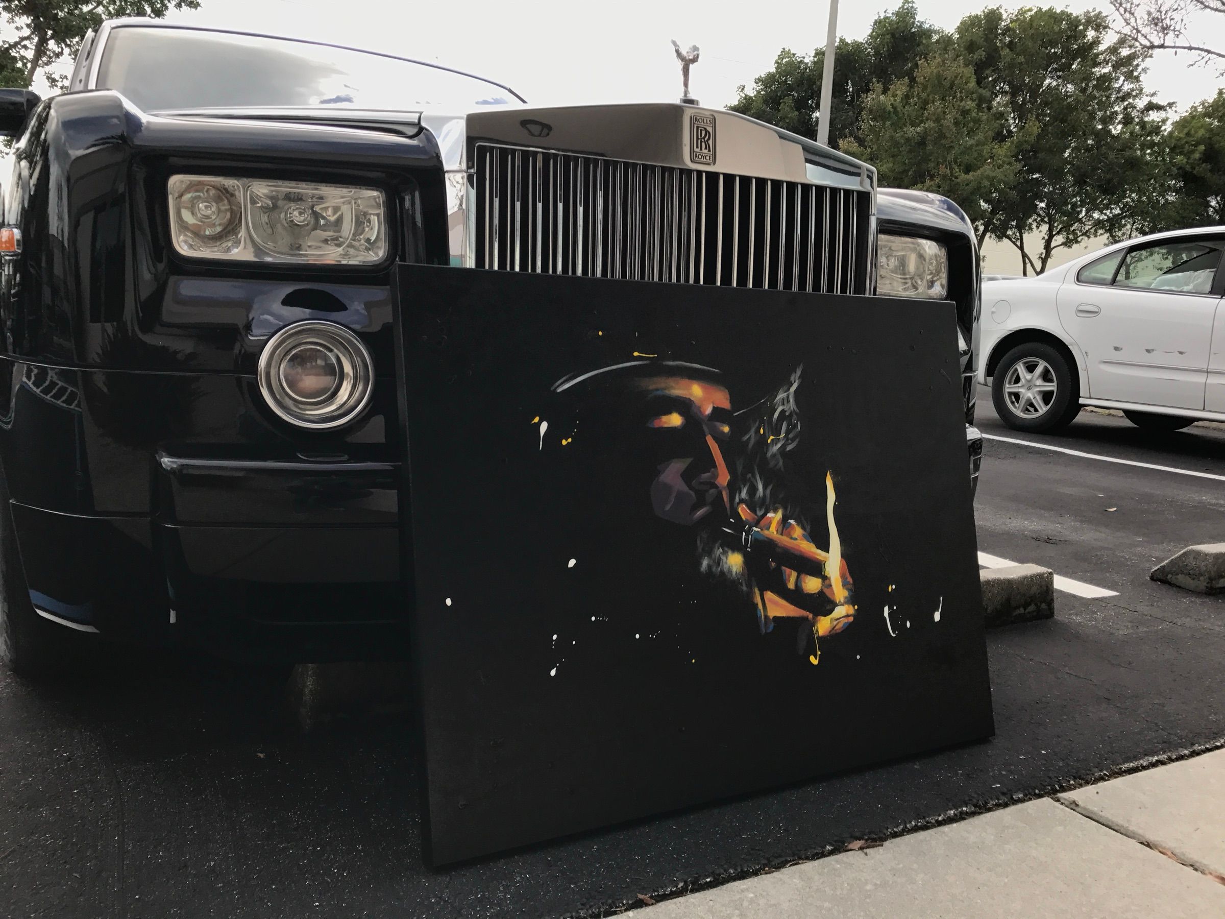 Painting of a man lighting a cigar, rendered in gold and amber on a black canvas, leaning on a Rolls-Royce
