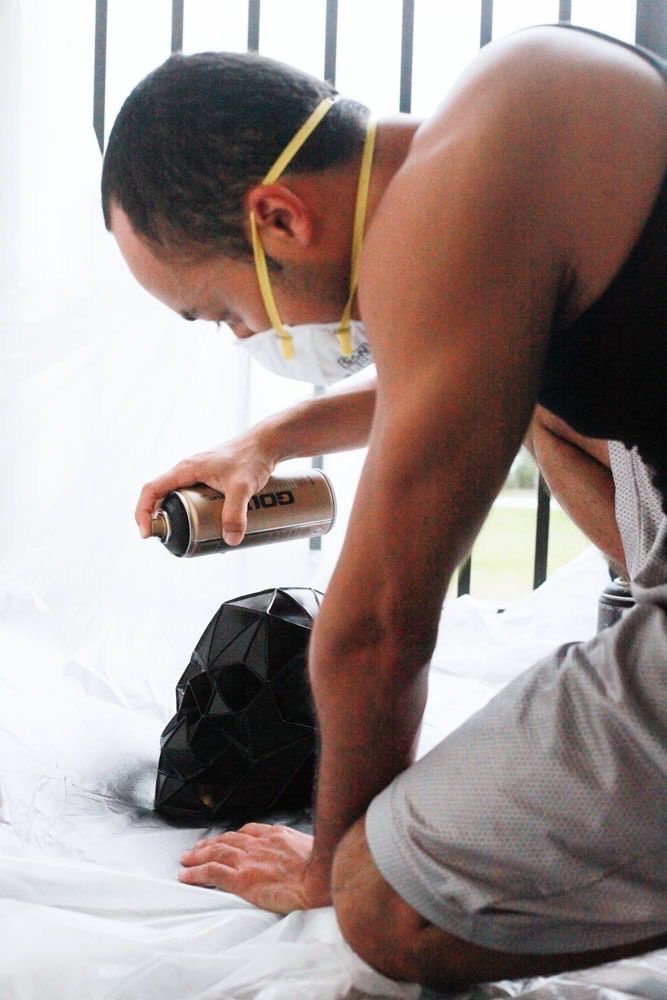 The artist in a respirator spray painting a sculpture