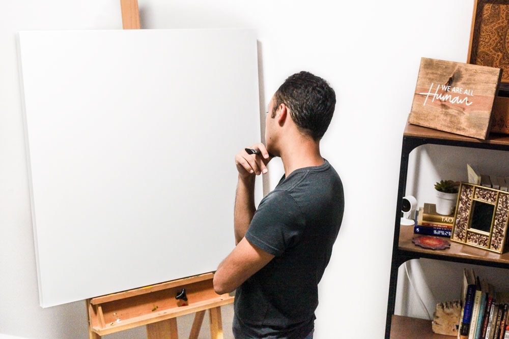 PUCHO in the studio, contemplating a blank white canvas on an easel