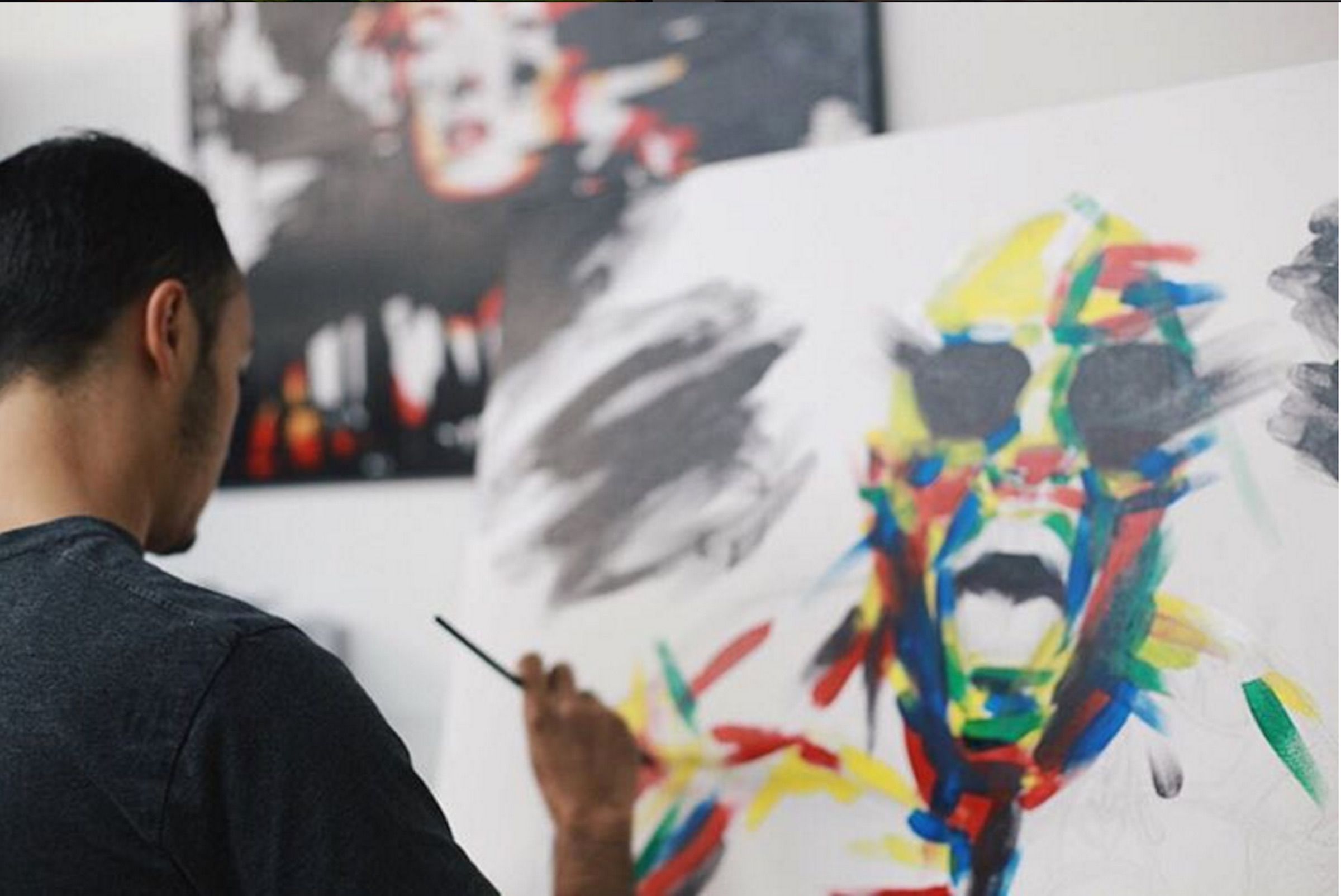The artist painting colorful strokes on a white canvas