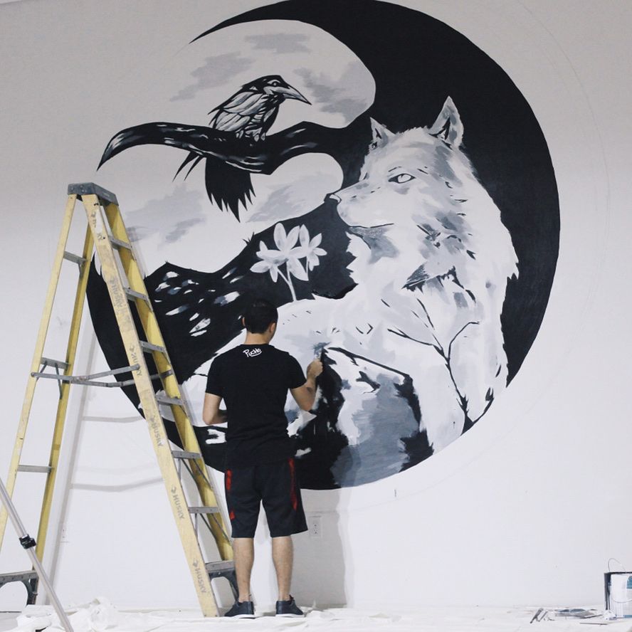 PUCHO painting a crescent moon mural with a wolf and a raven