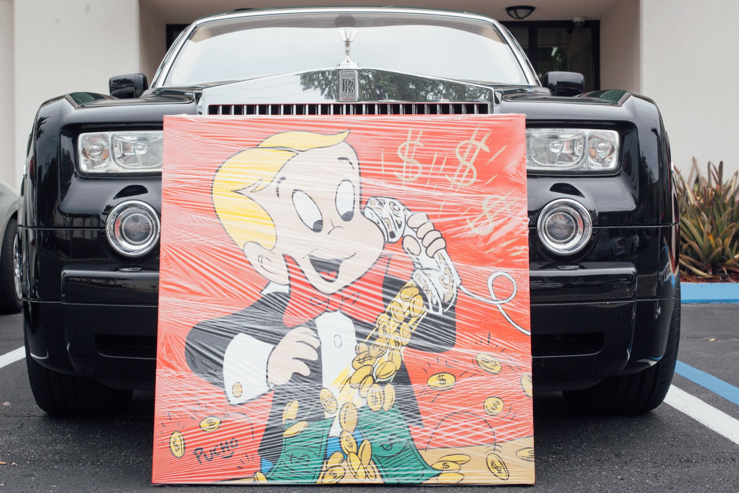 Wrapped pop art painting on red, delivered and leaning against a black Rolls-Royce